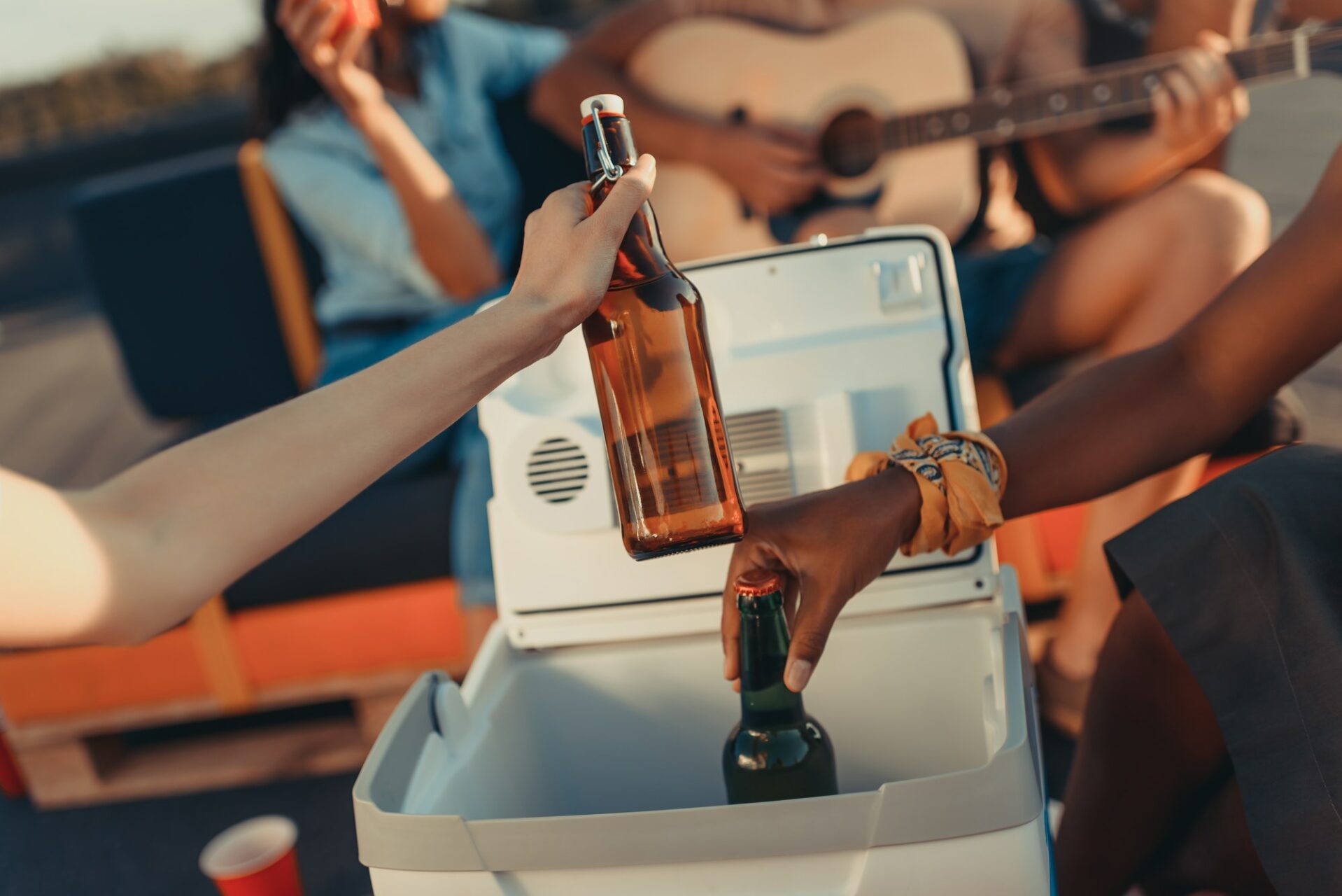 cropped shot of people taking beer out of portable fridge