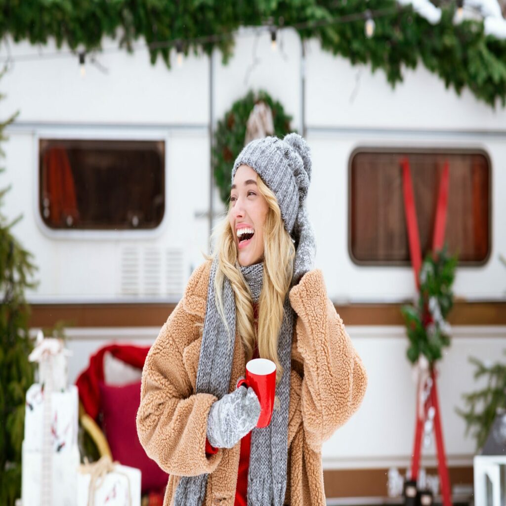 Winter Camping. Happy laughing girl enjoying cup of tea near campervan outdoors
