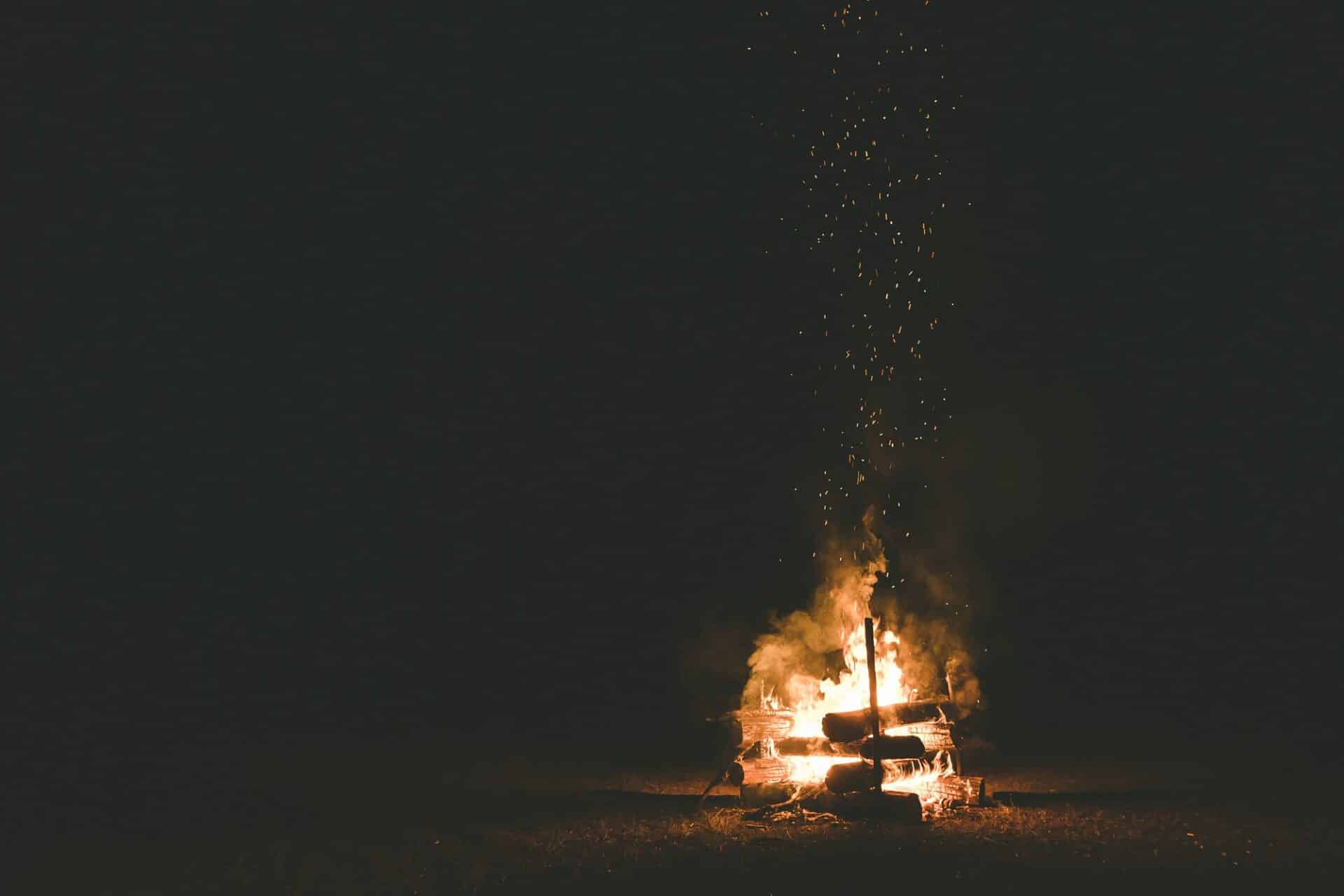 A campfire with sparks flying around in the dark night