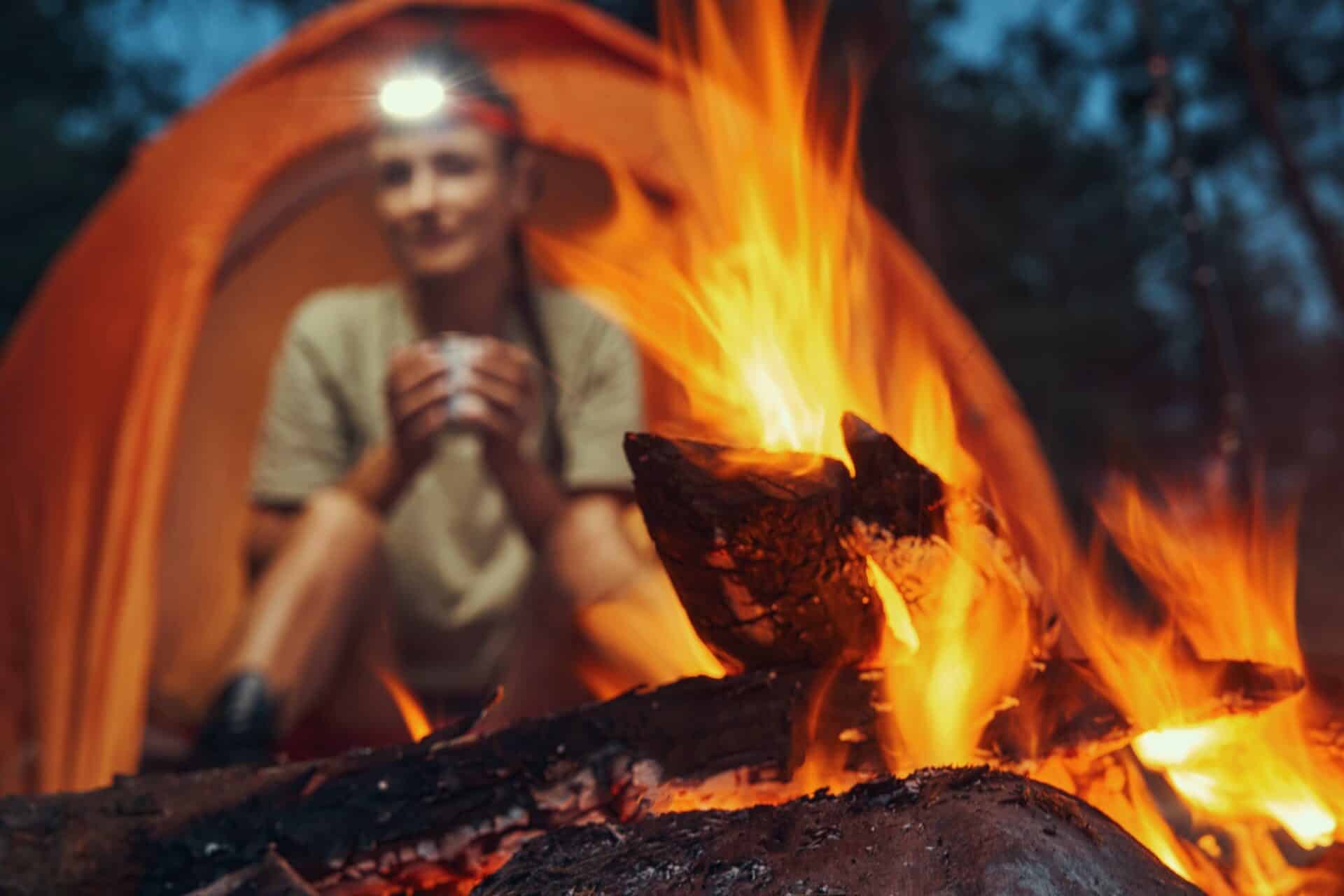Campfire burning before a woman in tent