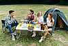 Guys sitting at the table during lunch in the camping and talking