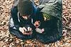 Hiking couple lying in sleeping bags looking at smartphones in forest, Monte San Primo, Italy