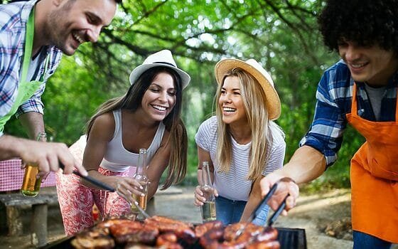 Happy friends camping and having a barbecue in nature