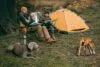Father and son sitting on camp-chairs at bonfire with a dog