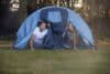 Couple Worried About Weather Looking Out Of Tent On Camping Trip In Countryside Together