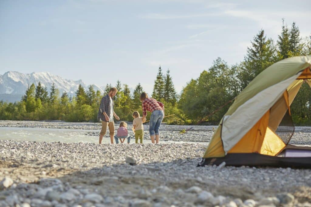 Rear view of family playing in river by tent, Wallgau, Bavaria, Germany