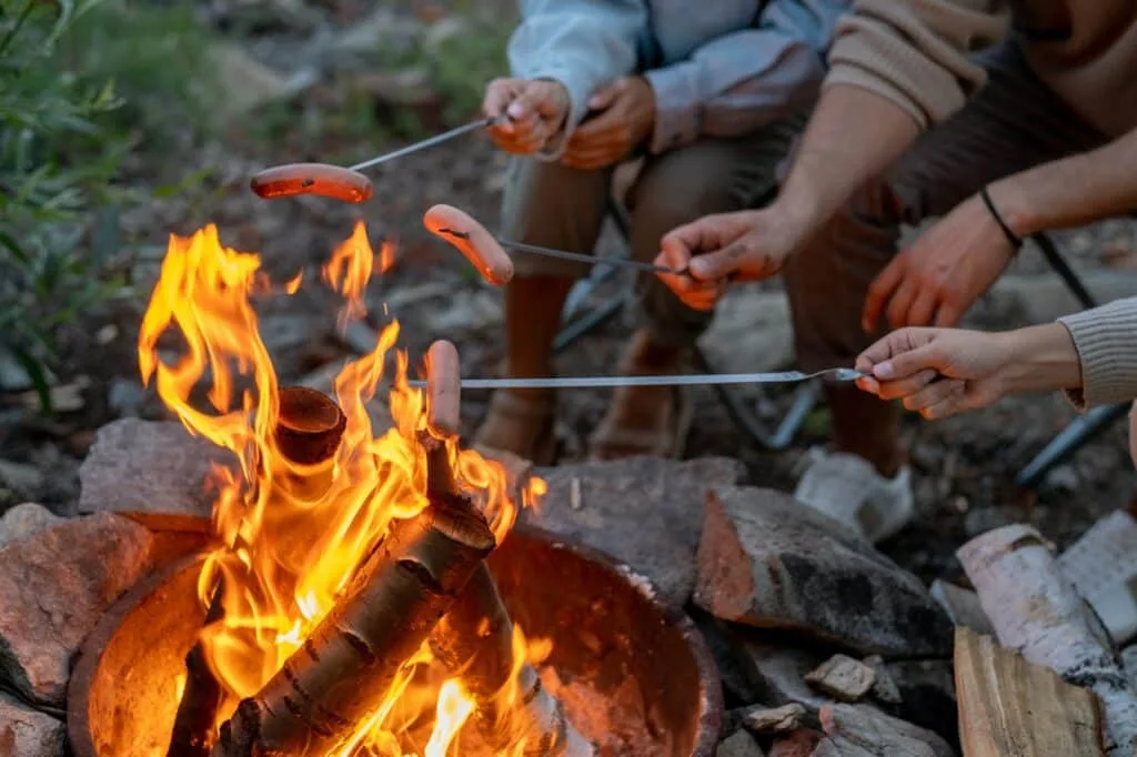 Camping Rezepte Familie: Einfache und leckere Gerichte für die ganze Familie 8 Young family of three cooking sausages over campfire