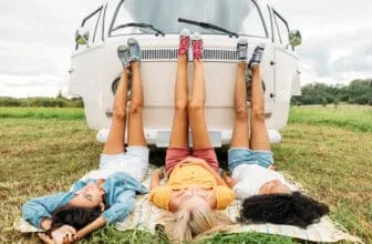 Three women lying on a blanket in front of a camper van