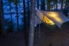 Camping tree hammock tent hanging in the forest by a lake at night