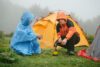 Travelers cooking near tents in rainy mountains