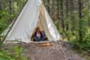 Woman sitting in canvas teepee on campsite