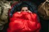 A young woman in a comfortable sleeping bag in a tent, top view. A tourist in a sleeping bag