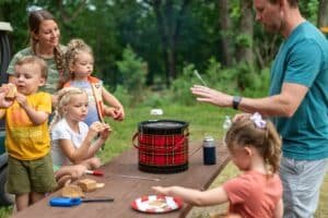 Family group roasting marshmallows over a camp stove