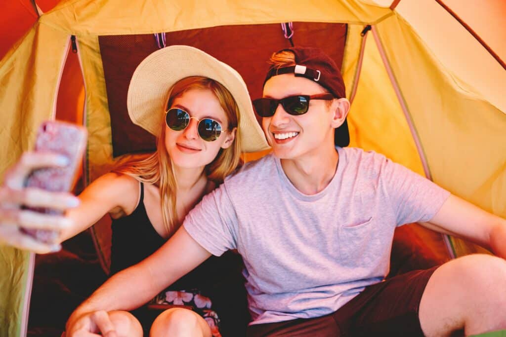 Couple of travelers taking selfie in camping tent