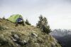 Young male hiker drinking coffee in front of tent on Klammspitze mountain, Oberammergau, Bavaria,