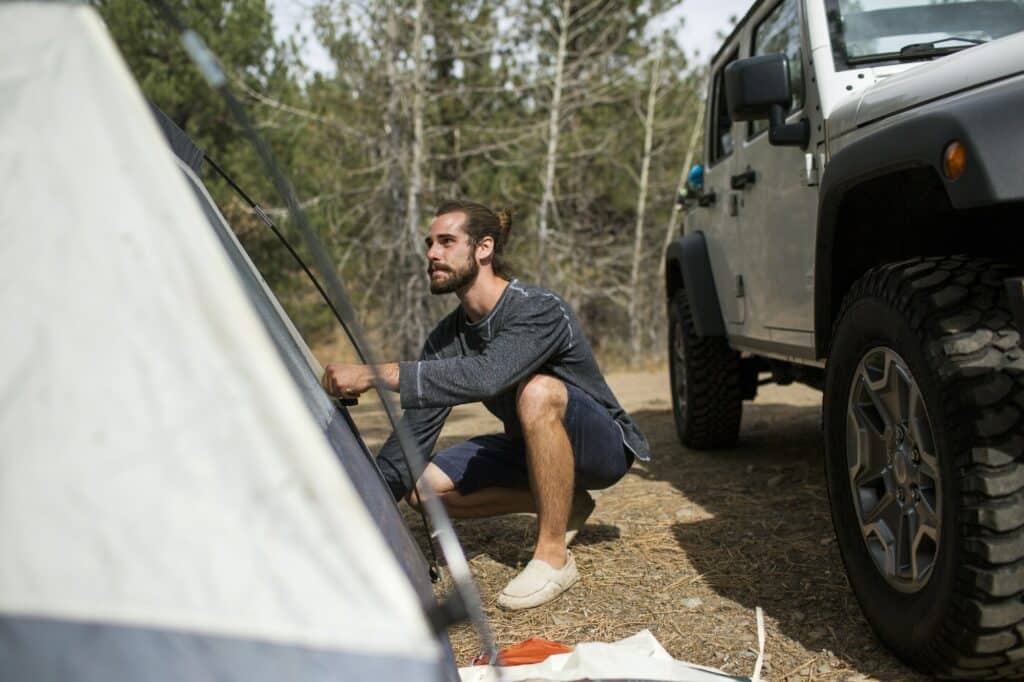 Young man erecting tent in forest, Lake Tahoe, Nevada, USA