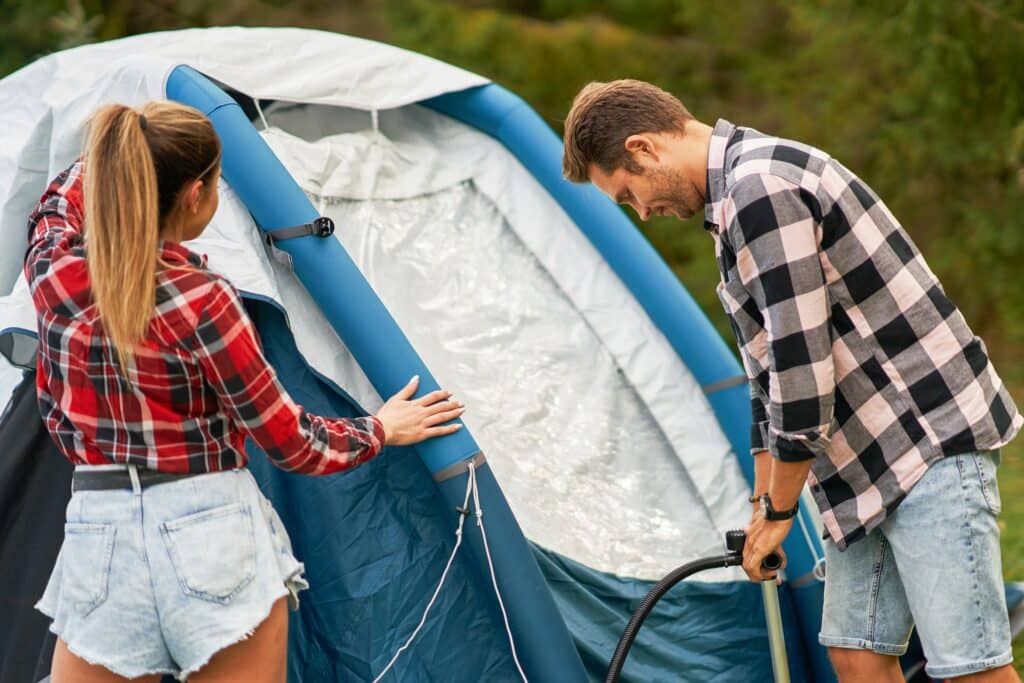 Young nice couple having fun on camping setting up tent