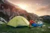 Female traveler in sleeping bag near the tent in the mountains