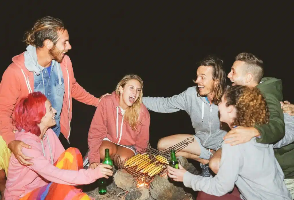 Camping Rezepte Familie: Einfache und leckere Gerichte für die ganze Familie 23 Happy friends camping together and cooking corn at night outdoor