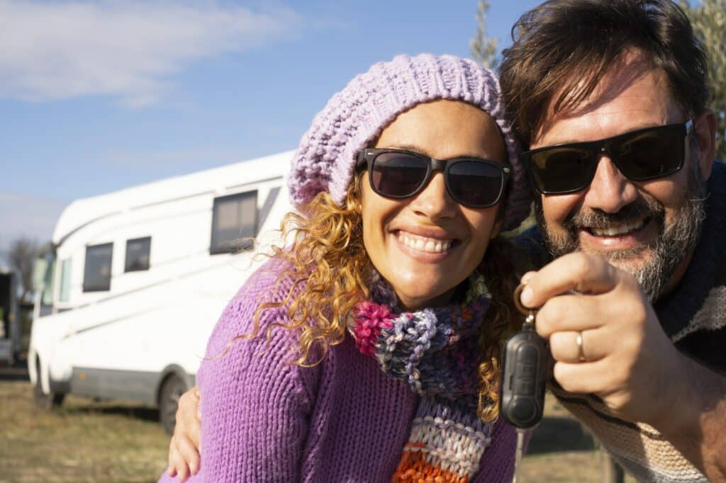 New camper van buyer people showing keys at the camera with happiness and big smile