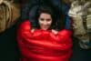 Portrait of a young woman who is cozy and warm in a red sleeping bag