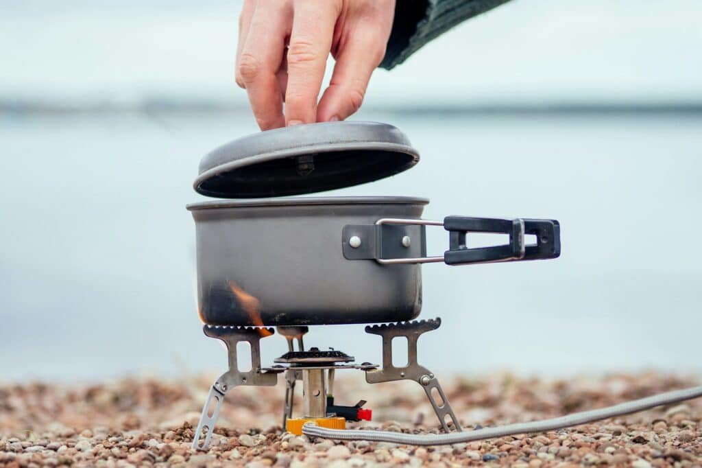 The pan with the porridge stands on the gas burner (Camping Stove). On the background of the river