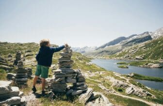Rear view of boy on mountain stacking rocks, Hinterrhein, Switzerland