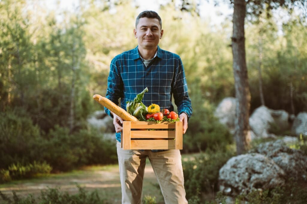 Veganes Campen für Einsteiger: Einfache Rezepte und praktische Tipps für die Outdoor-Küche 6 Caucasian man male holding wooden crate with vegan groceries organic vegetables and bread baguette