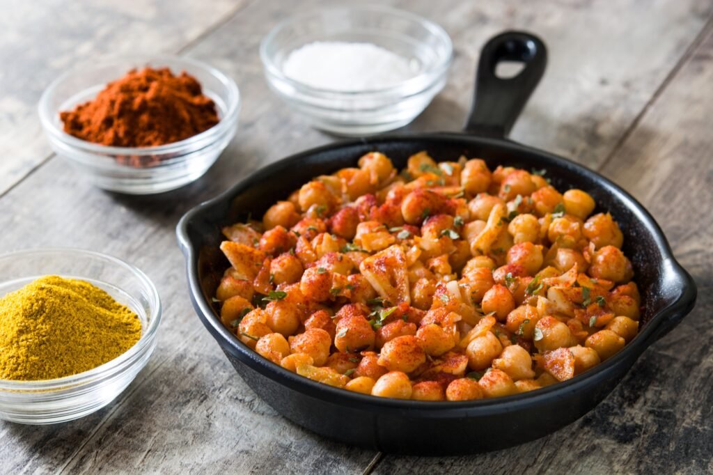 Pflanzliche Rezepte für Outdoor-Abenteuer: 10 energiereiche Ideen für nachhaltiges Camping 4 Chickpeas with spices and herbs in a cast iron pan