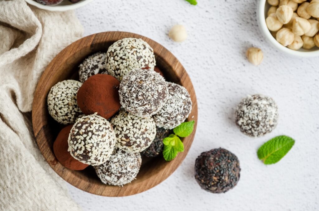 Pflanzliche Rezepte für Outdoor-Abenteuer: 10 energiereiche Ideen für nachhaltiges Camping 11 Energy balls. Truffles of dates, walnuts, hazelnuts and cocoa in a wooden bowl. Healthy dessert