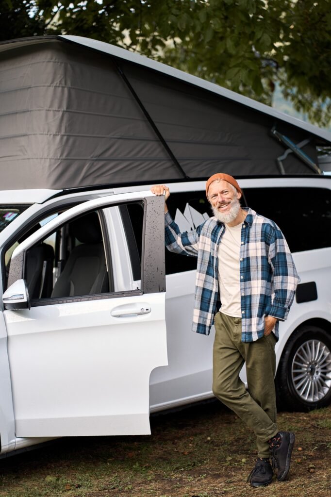 Happy older man traveler standing with camper van, campervan rentals.