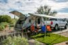 A scenic campsite in Apache Junction, AZ showcasing a Freesolo motorhome with camping chairs and pickup truck.