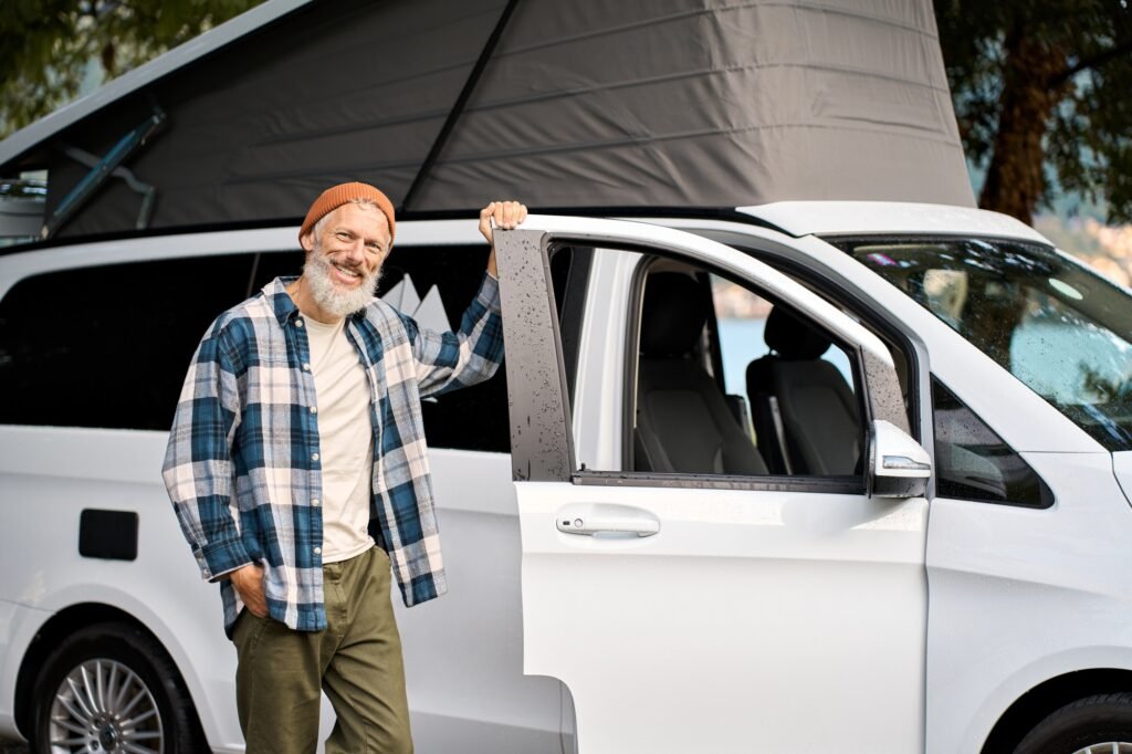 Fernreisemobil-Ratgeber: Der komplette Guide zur optimalen Ausstattung 2 Happy older man traveler standing with camper van, campervan rentals.