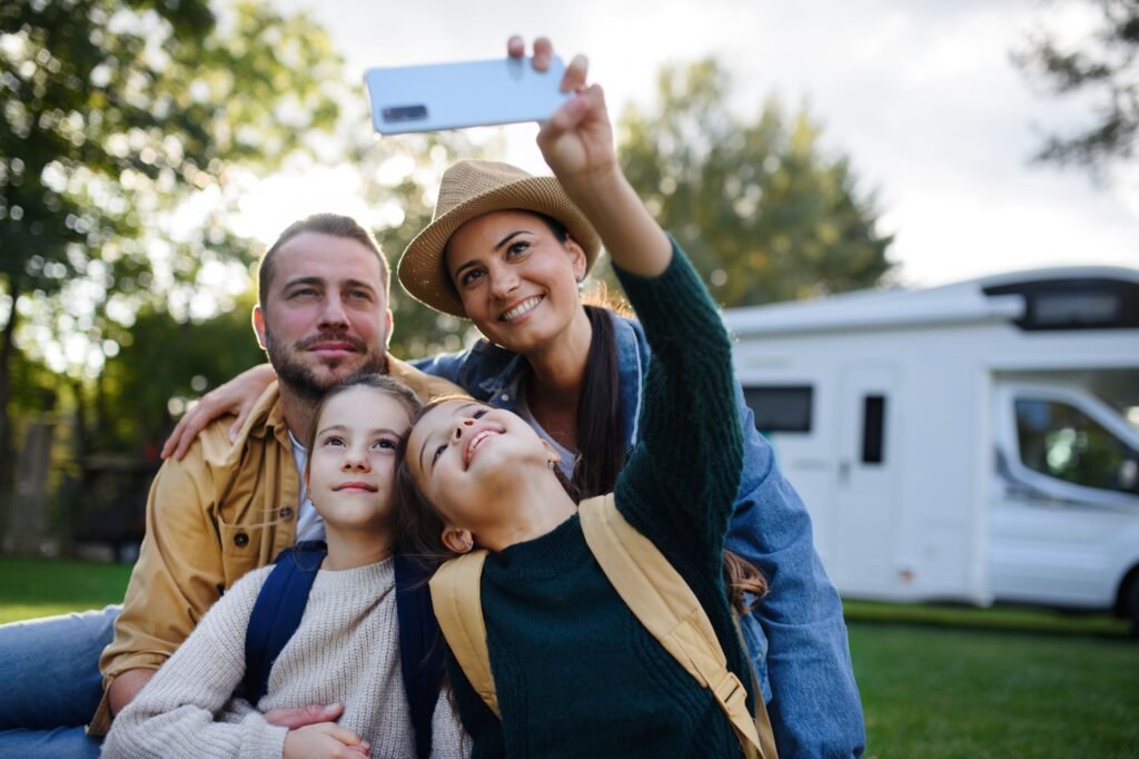 Der ultimative Guide zum Caravaning: Tipps für unvergessliche Reisen 3 Happy young family with two children taking selfie with caravan at background outdoors.