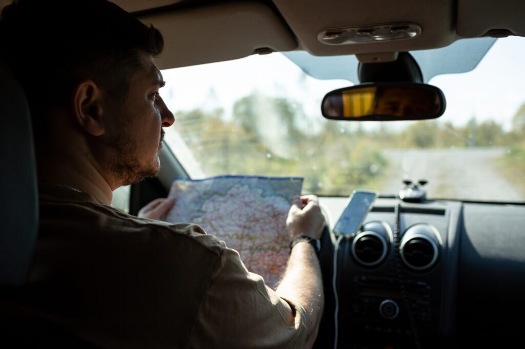 A man in a car is studying a road map