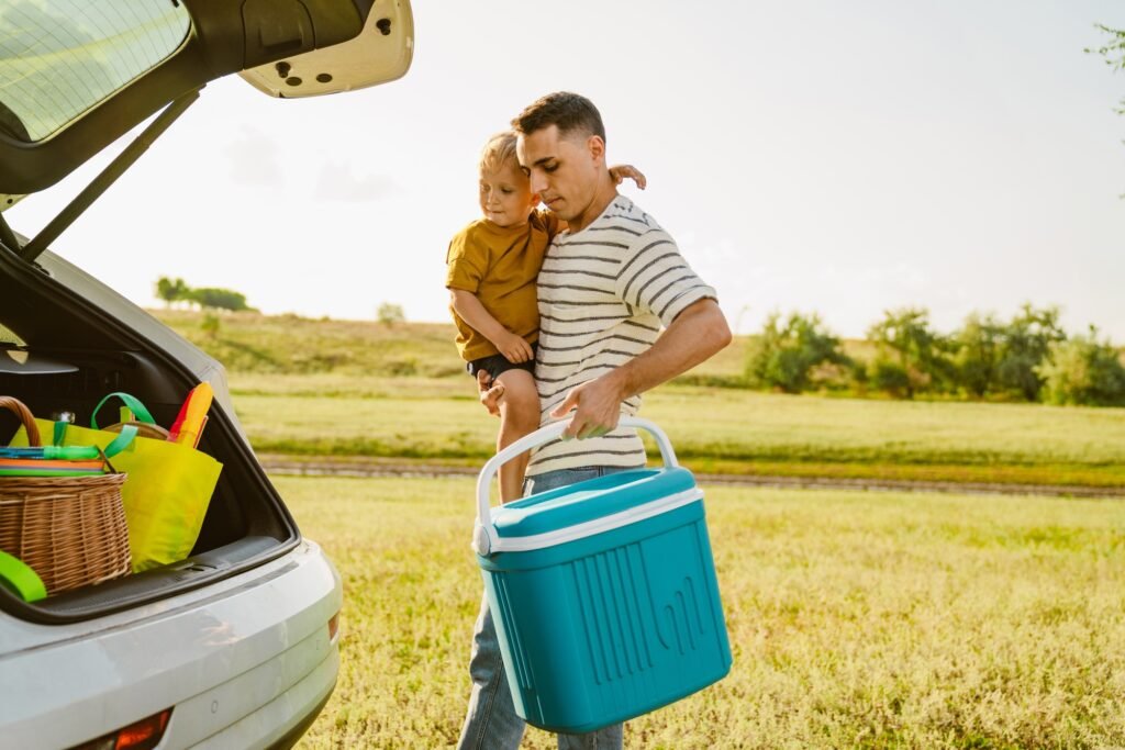 Wie lange halten Kühlboxen kalt? Praktische Tipps für längere Kühlung 1 Young father holding his son and cooler bag by car trunk outdoors
